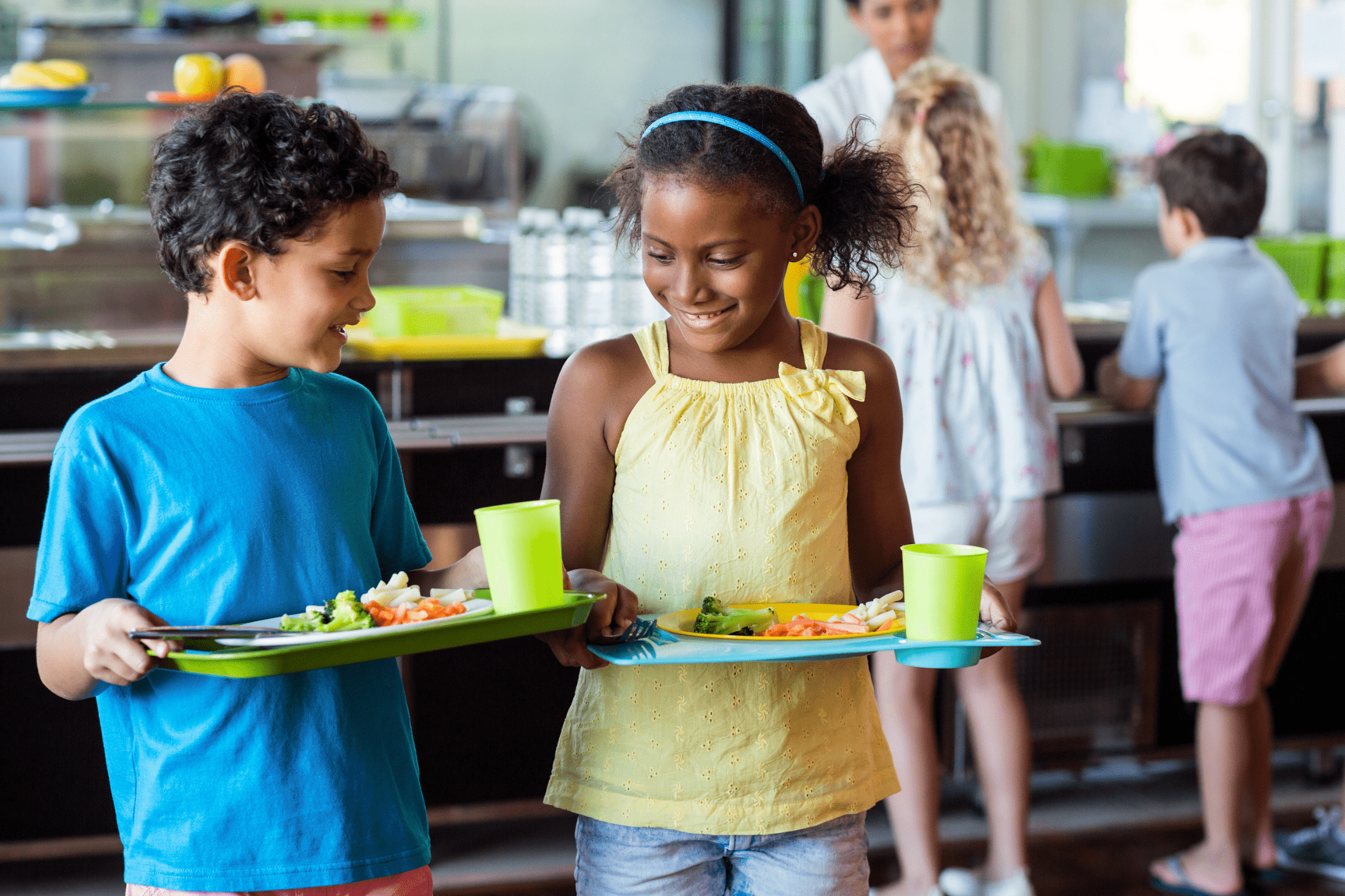 Crianças carregando bandejas com alimentação educacional.